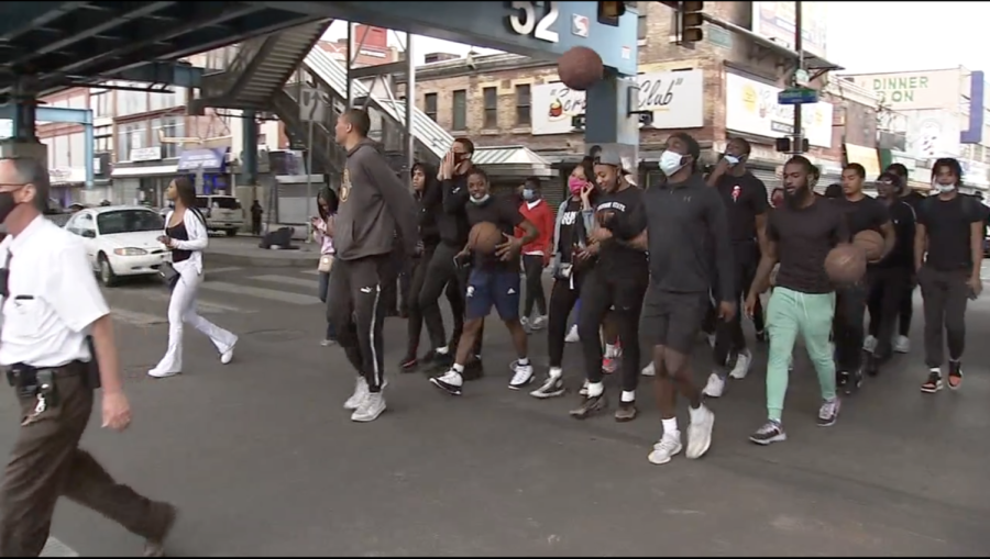 Dhamir Cosby-Roundtree marching with a group of other athletes in West Philadelphia on 52nd Street.