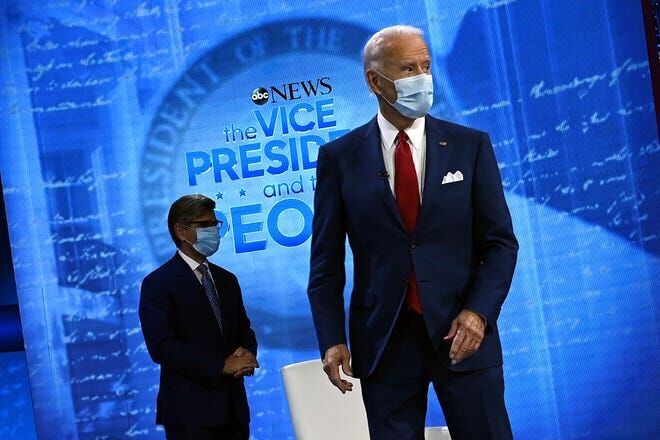 Former Vice President Joe Biden stands on stage, wearing a mask at his Townhall.