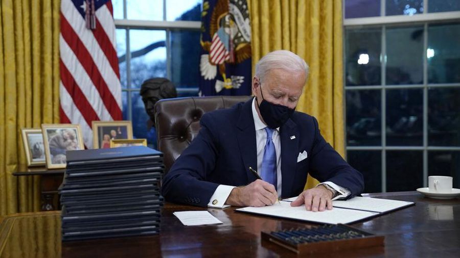 President Biden signing executive orders in the Oval Office