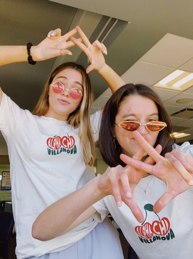 Alpha Chi Omega sisters Abigail Lukas (left) and Elena Rouse (right) do their sorority hand sign during recruitment partner rounds.