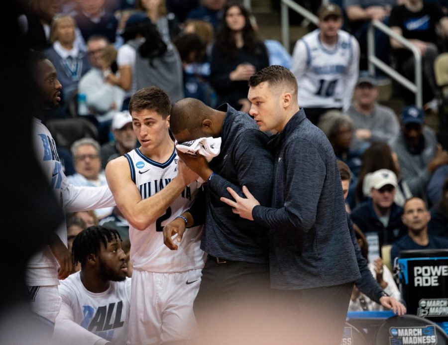 Director of basketball operations Joey Flannery and graduate guard Collin Gillespie hold Anderson after the blow.