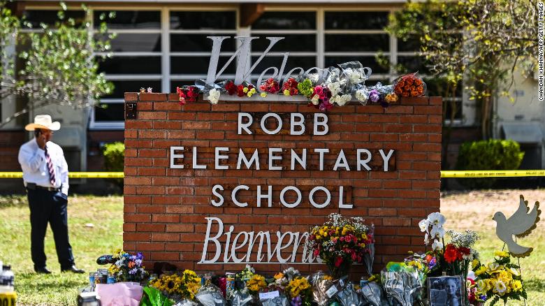 Crosses and flowers stand outside of Robb Elementary. 