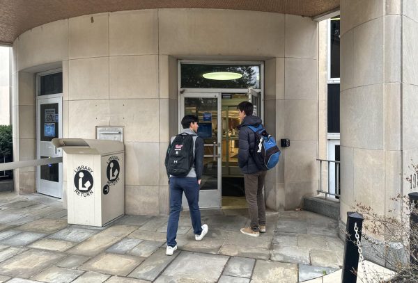 A student holds the door for another student as they walk into Falvey Library.
